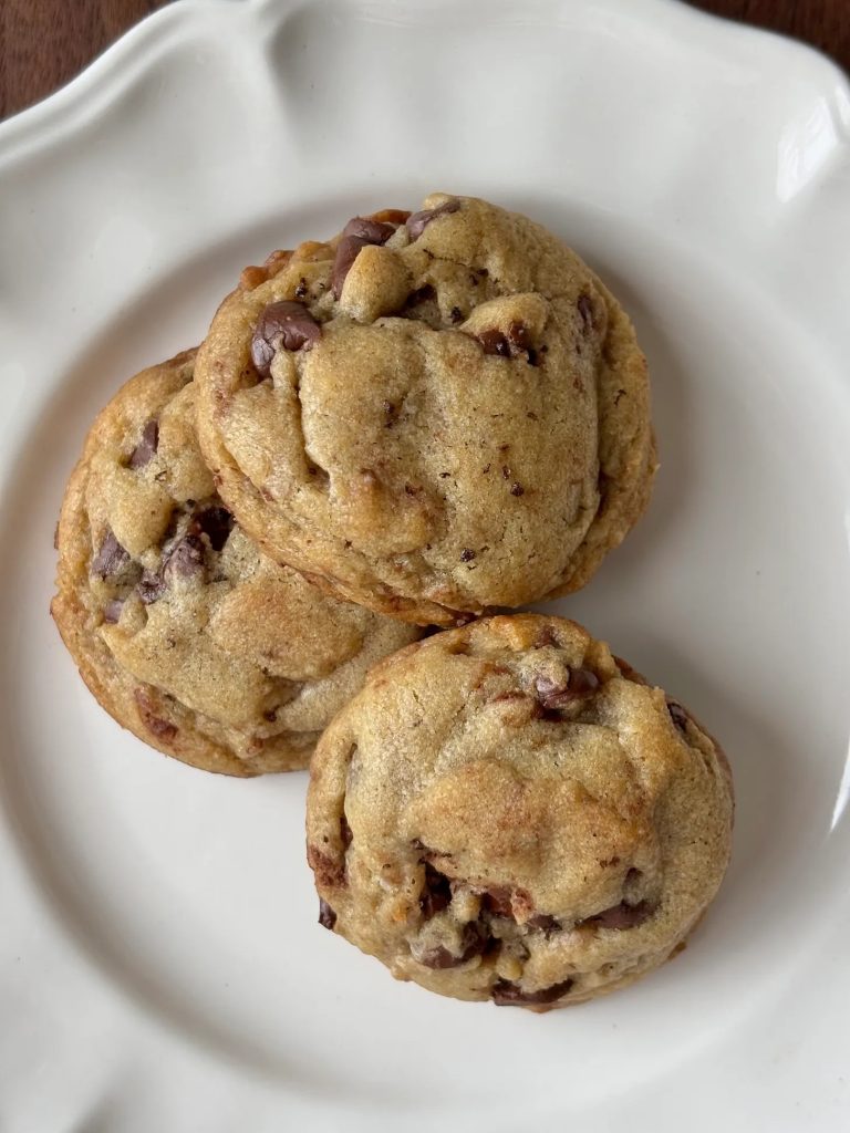 a plate of three chocolate chip cookies on a white plate