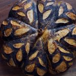 Pumpkin shaped pumpkin spice sourdough loaf with black cocoa powder and wheat scoring
